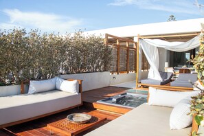 A rooftop terrace with a wooden deck, a white outdoor sofa, and a canopy. - Avgoustos Suites - Adults only (Naxos)