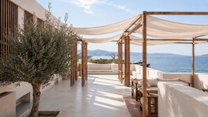 A rooftop terrace with a view of the sea, wooden pergolas, and seating areas. - Avgoustos Suites - Adults only (Naxos)