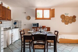 Une cuisine compacte avec une table à manger pour six personnes, un four à micro-ondes et un téléviseur posé sur le comptoir.