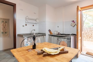 A kitchen with a wooden table, wine glasses, a cutting board, and a knife.