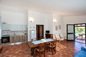 A kitchen with a dining area, a TV, and a door leading to an outdoor space.