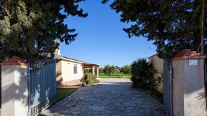 A stone pathway leading to a house with a metal gate, surrounded by trees. - Holiday Home Casa Barvis with Garden, A/C, Terrace and Wi-Fi (Orosei)