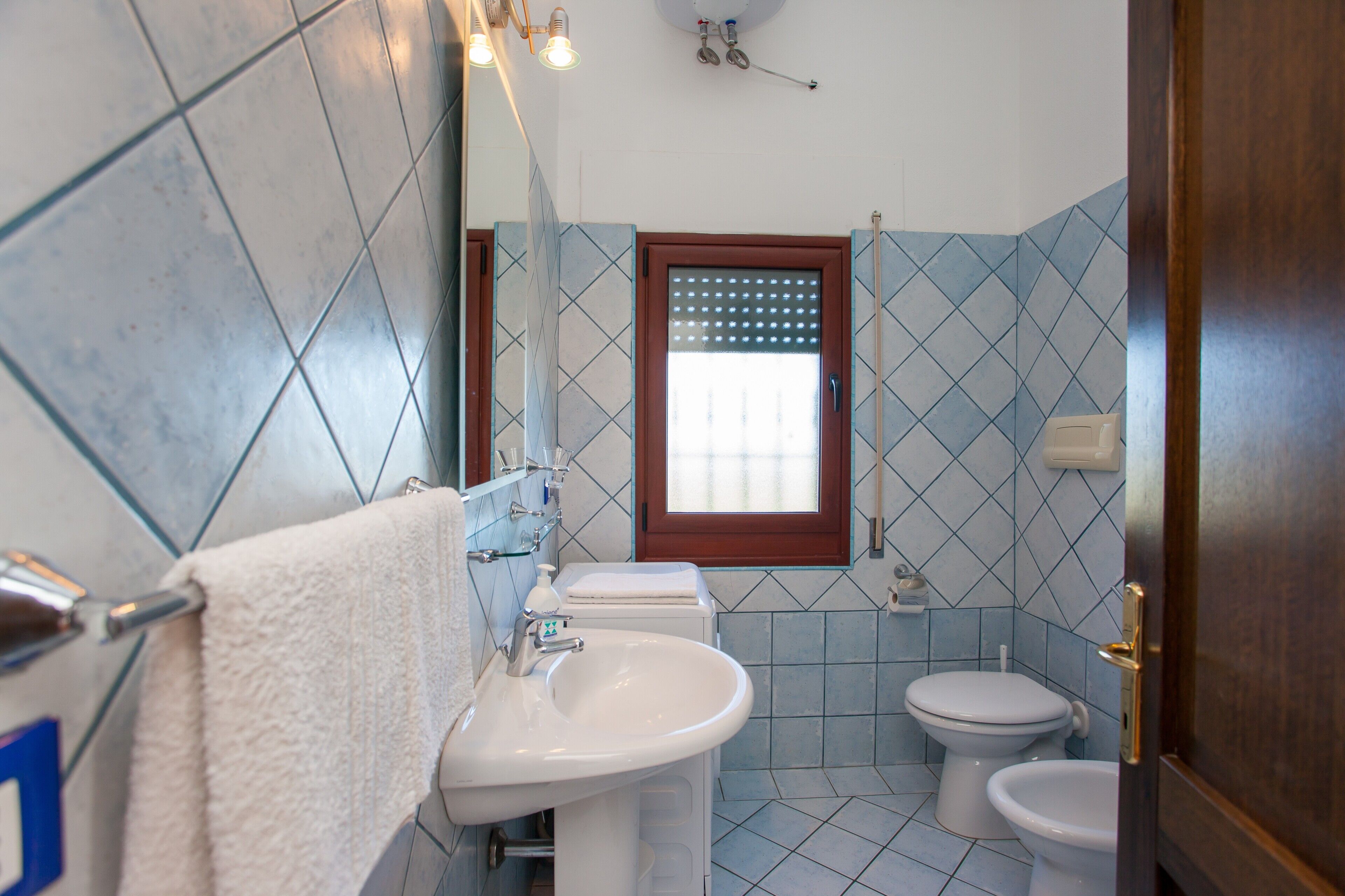 A bathroom with a sink, toilet, and mirror.
