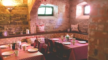 Un restaurant aux murs de pierre, décoré avec des motifs en forme de cœur, et dont les tables sont dressées avec des assiettes et des tasses.