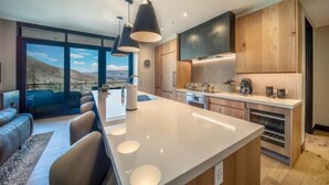 A modern kitchen with a central island, wooden cabinets, and pendant lighting. - One Snowmass East 303 (Snowmass)