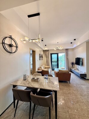 Une chambre d’hôtel moderne dotée d’un coin repas, d’un canapé, d’une télévision et d’une grande fenêtre.