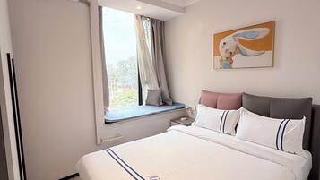 A bedroom with a large bed, a window with curtains, a painting on the wall, and a ceiling light.