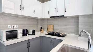 Une cuisine moderne avec des meubles gris, un évier en acier inoxydable et un four à micro-ondes.