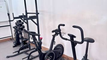 A gym with stationary bikes, a treadmill, and a rack of dumbbells.