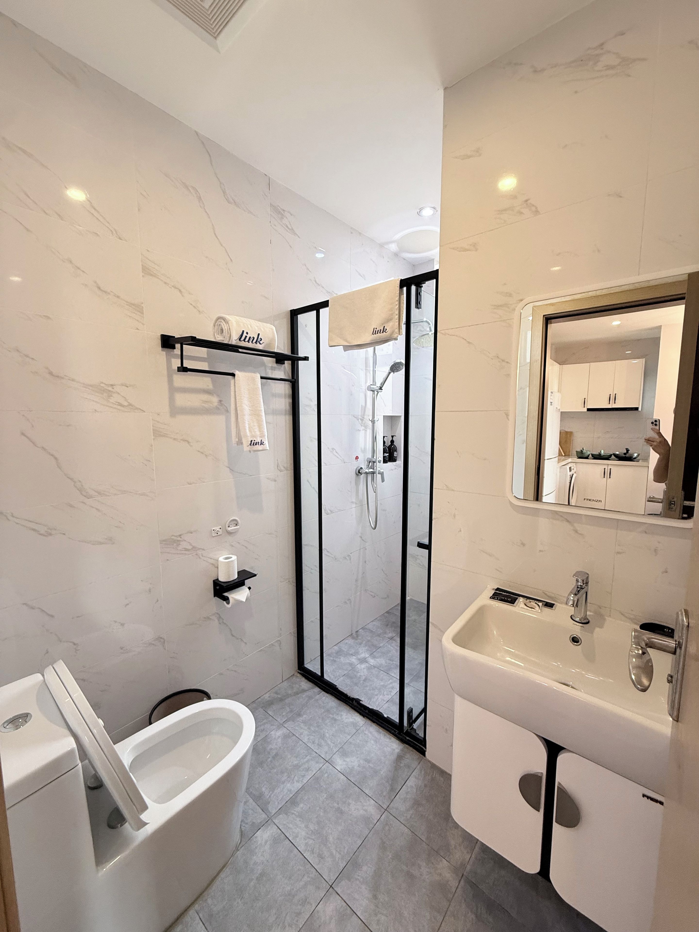 A modern bathroom with a glass-enclosed shower, a white bathtub, and a sink with a mirror above.