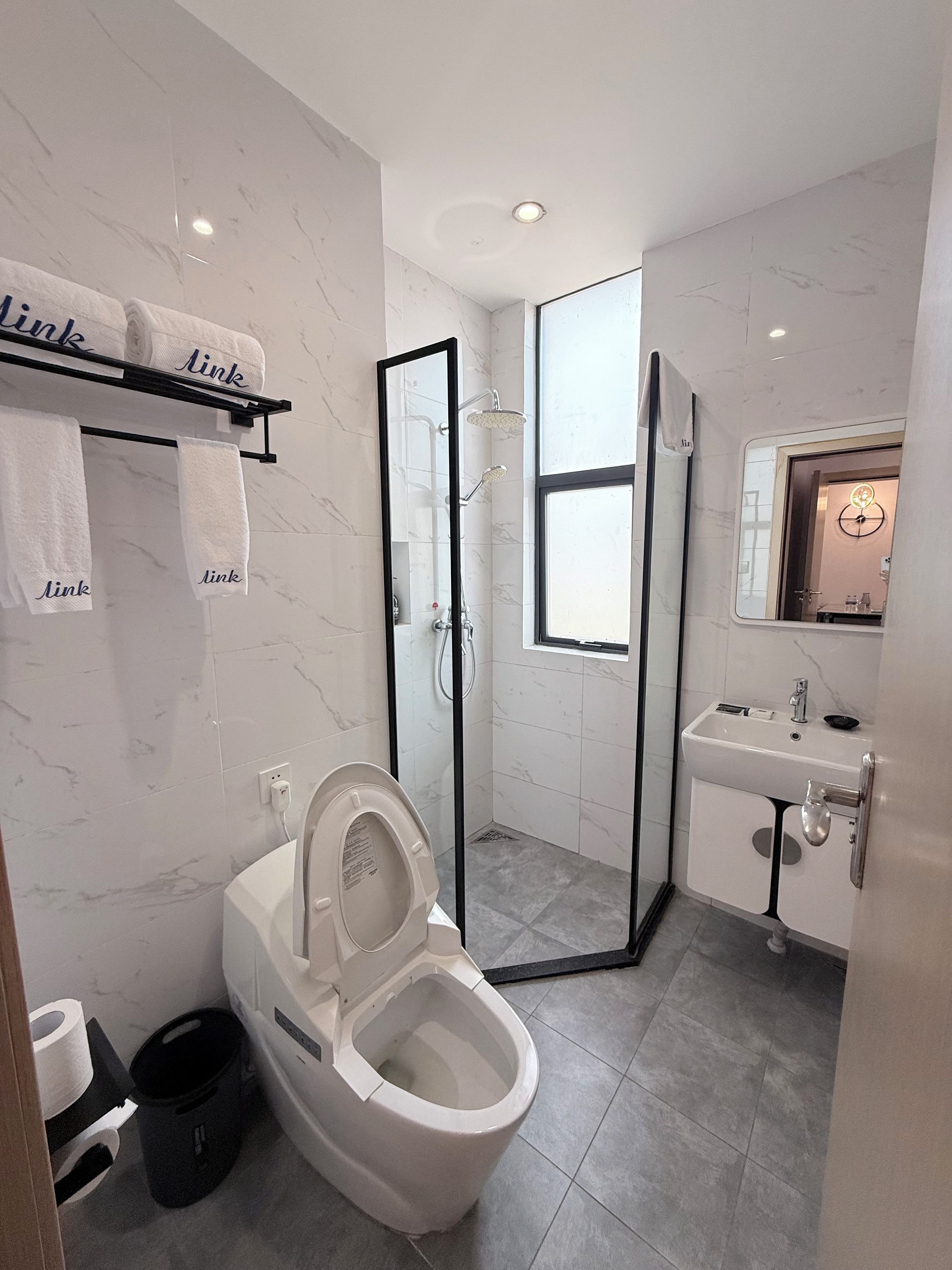 A modern bathroom with a toilet, shower, and sink.