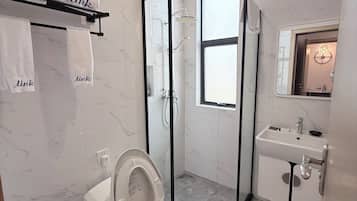 A modern bathroom with a toilet, shower, and sink.