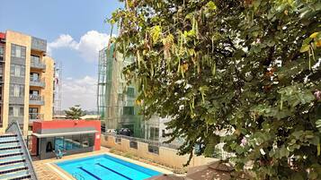 A swimming pool area with a view of a building and a tree.