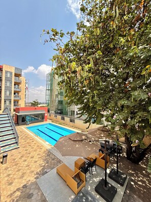 Un espace piscine avec vue sur un immeuble et un arbre.