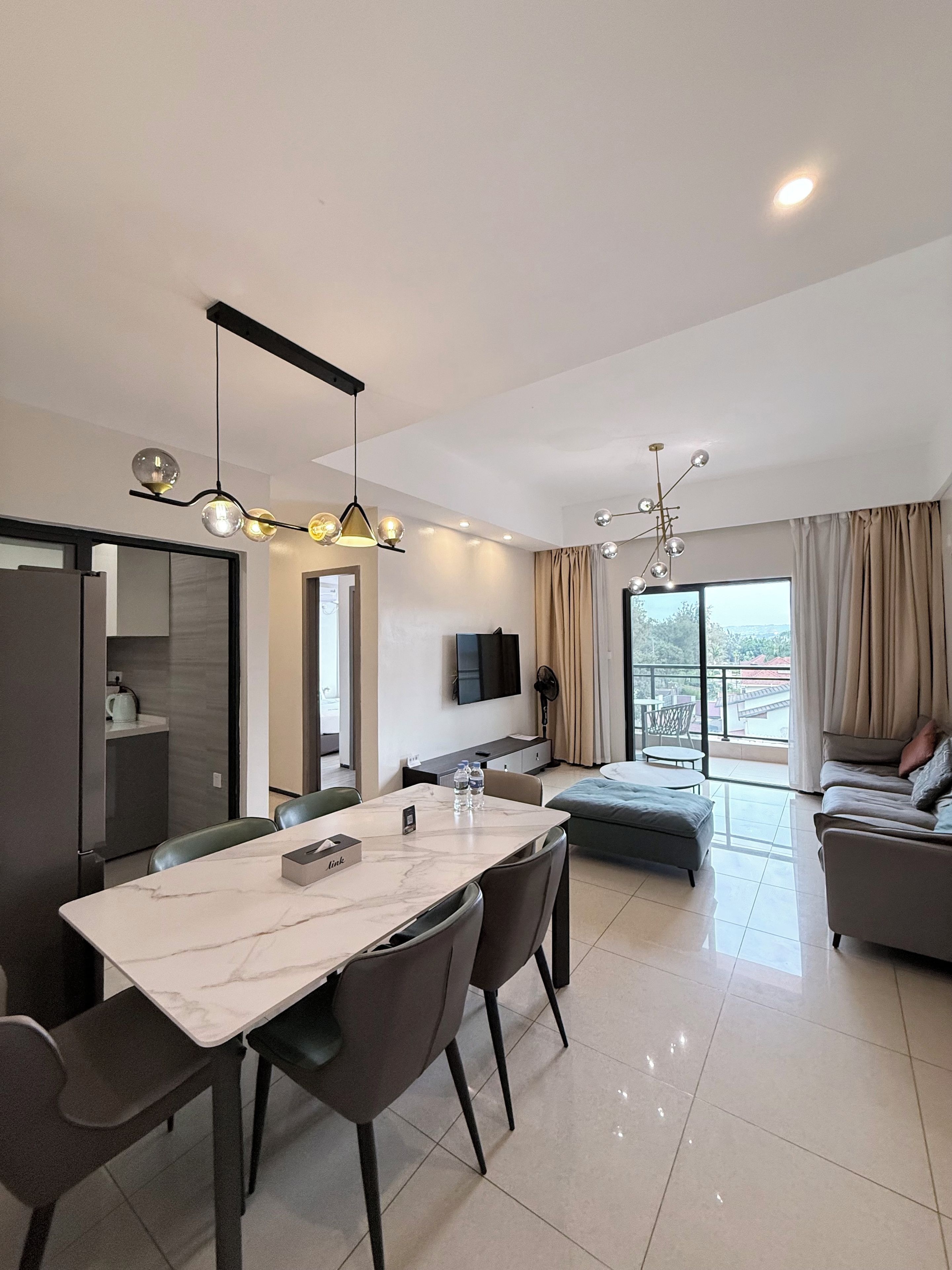 Ein modernes Hotelzimmer mit Essbereich, einer Couch und einem Balkon mit Blick.