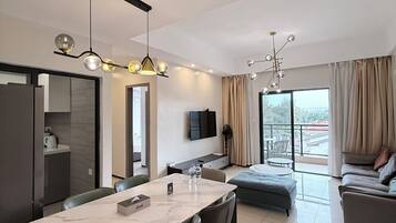 Ein modernes Hotelzimmer mit Essbereich, einer Couch und einem Balkon mit Blick.