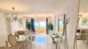 Un salon moderne avec un coin repas, un grand miroir et une vue sur la mer.