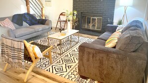 Sala de estar com lareira, dois sofás, mesa de centro e tapete estampado.