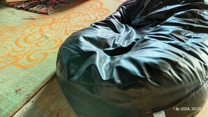Ein rustikaler Holzraum mit einem roten Sofa, einem schwarzen Sitzsack und einer Holzkiste.