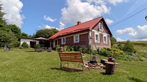 Ein Haus mit rotem Dach, ein Garten mit einer Bank und ein Fahrrad.