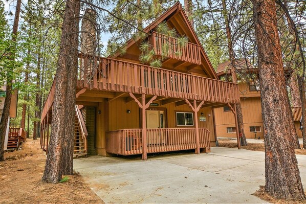 A cabin with a two-story structure, a balcony, and a front porch.