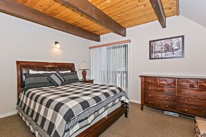 Ein Schlafzimmer mit einem Holzbett, einem Schminktisch, einem Fenster mit Jalousien und einem gerahmten Bild an der Wand.