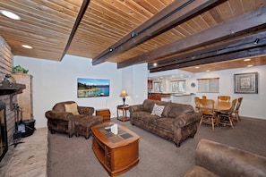 A spacious living area with a fireplace, leather sofas, a coffee table, and a dining set. - Redwood Lodge by Destination Big Bear : Close to Snow Summit and Short Drive to Lake & Village! Air Hockey! (Big Bear Lake)