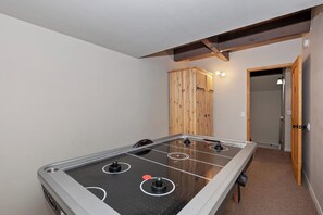 A room with a foosball table, a wooden wardrobe, and a door leading to another room.