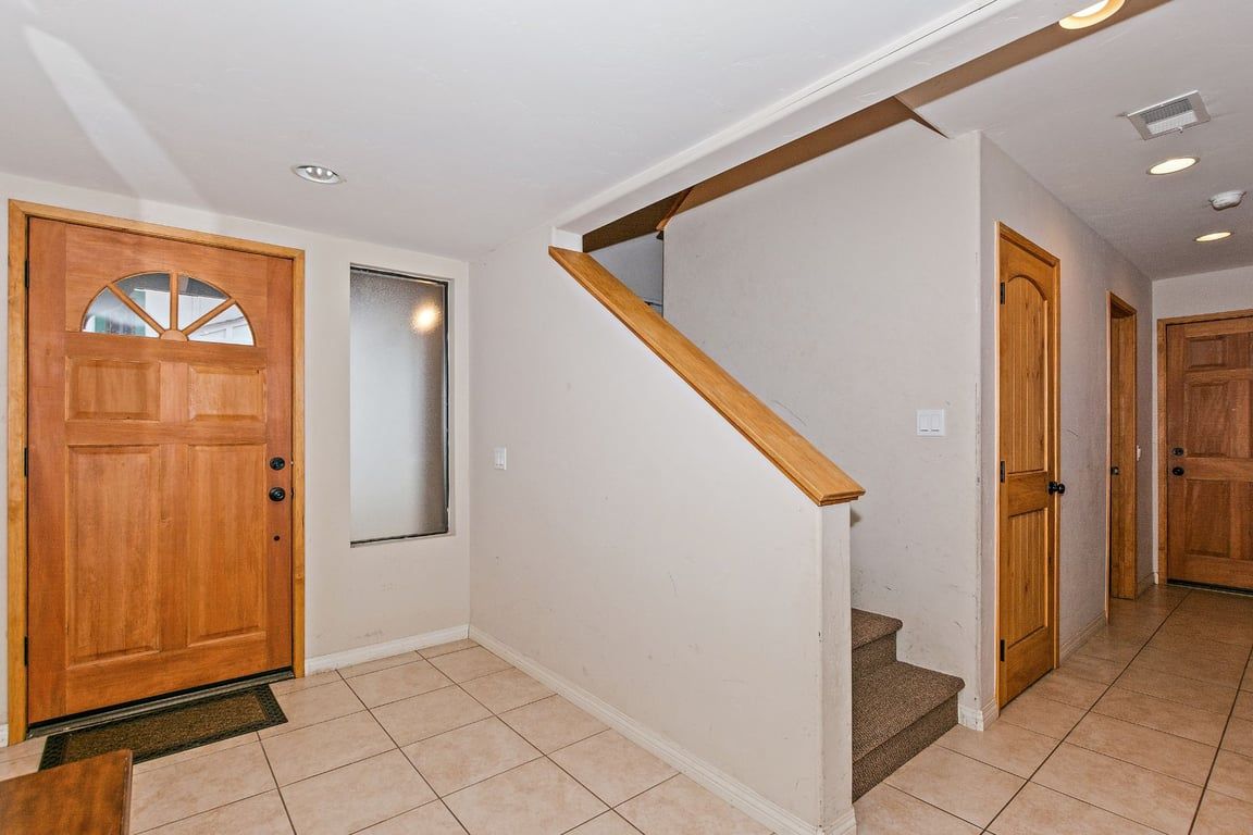 Un couloir avec une porte en bois, un miroir et un escalier.
