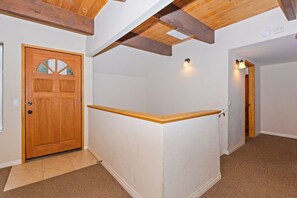 A hallway with a wooden door, a white wall, and a wooden ceiling beam. - Redwood Lodge by Destination Big Bear : Close to Snow Summit and Short Drive to Lake & Village! Air Hockey! (Big Bear Lake)