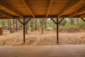 A covered wooden deck with a view of a forested area.