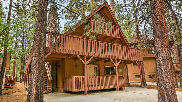 A cabin with a balcony, surrounded by trees.