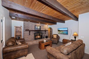 A cozy living room with a fireplace, leather sofas, and a television mounted on the wall.
