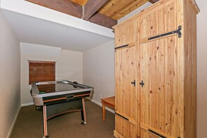Ein Zimmer mit Billardtisch, Holzschränken und einem Fenster mit Jalousien.