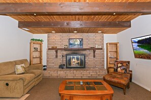 A cozy living room with a fireplace, a sofa, a coffee table, and a television. - Redwood Lodge by Destination Big Bear : Close to Snow Summit and Short Drive to Lake & Village! Air Hockey! (Big Bear Lake)