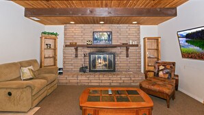 A cozy living room with a fireplace, a couch, a coffee table, and a bookshelf.