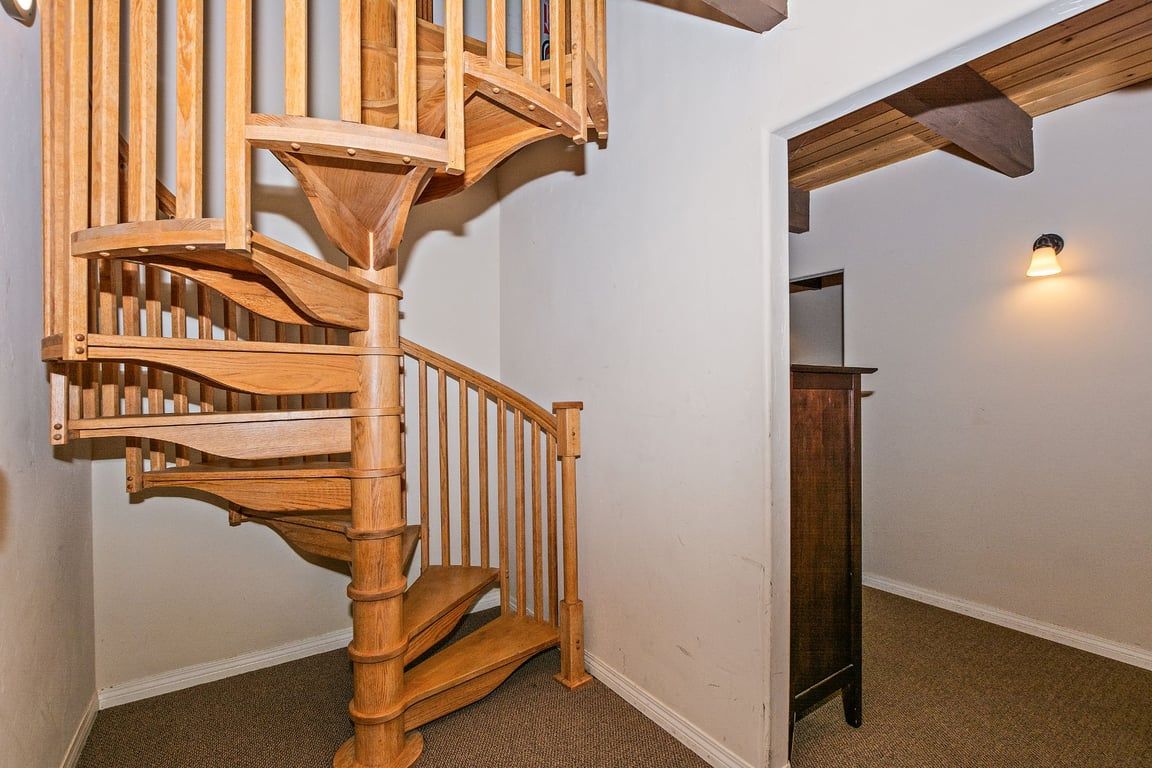Una escalera en espiral de madera con barandilla y rellano.