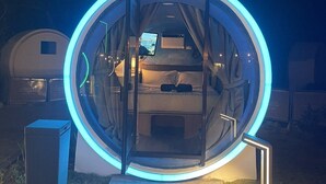 A circular structure with a bed inside, illuminated by blue lights, and a pathway leading to it. - Cocoons Casobe (Calatagan)