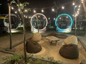 An outdoor seating area with bean bags and circular light installations. - Cocoons Casobe (Calatagan)