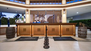 A reception area with a wooden counter, two receptionists, and a decorative backdrop. - Cocoons Casobe (Calatagan)