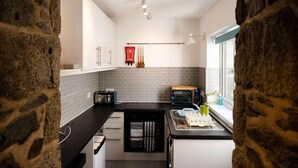 Une cuisine avec des meubles blancs, des carreaux gris, un plan de travail noir et une fenêtre donnant sur un beau paysage.