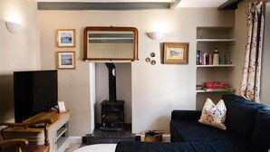 Un salon chaleureux avec une cheminée, un téléviseur, un canapé et une bibliothèque.
