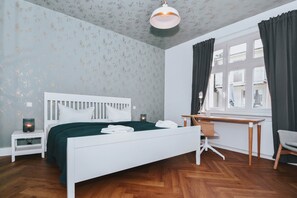 A bedroom with a white bed, a desk, a chair, a nightstand, and a window with curtains. - Modern vacation rental in Ahlbeck, just 400 meters from the beach (Seebad Ahlbeck)