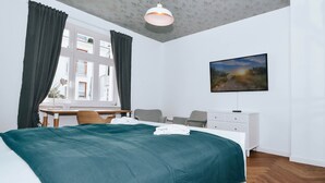 Ein Schlafzimmer mit Bett, Schreibtisch, Stuhl, Schminktisch und einem Bild an der Wand.
