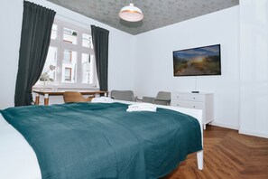 Quarto com cama, escrivaninha, cadeira, cômoda e um quadro na parede.
