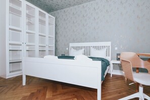 A bedroom with a white bed, a wooden chair, a white desk, and a wardrobe with multiple shelves. - Modern vacation rental in Ahlbeck, just 400 meters from the beach (Seebad Ahlbeck)
