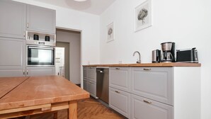 Eine moderne Küche mit grauen Schränken, einem Holztisch und einer Kaffeemaschine.