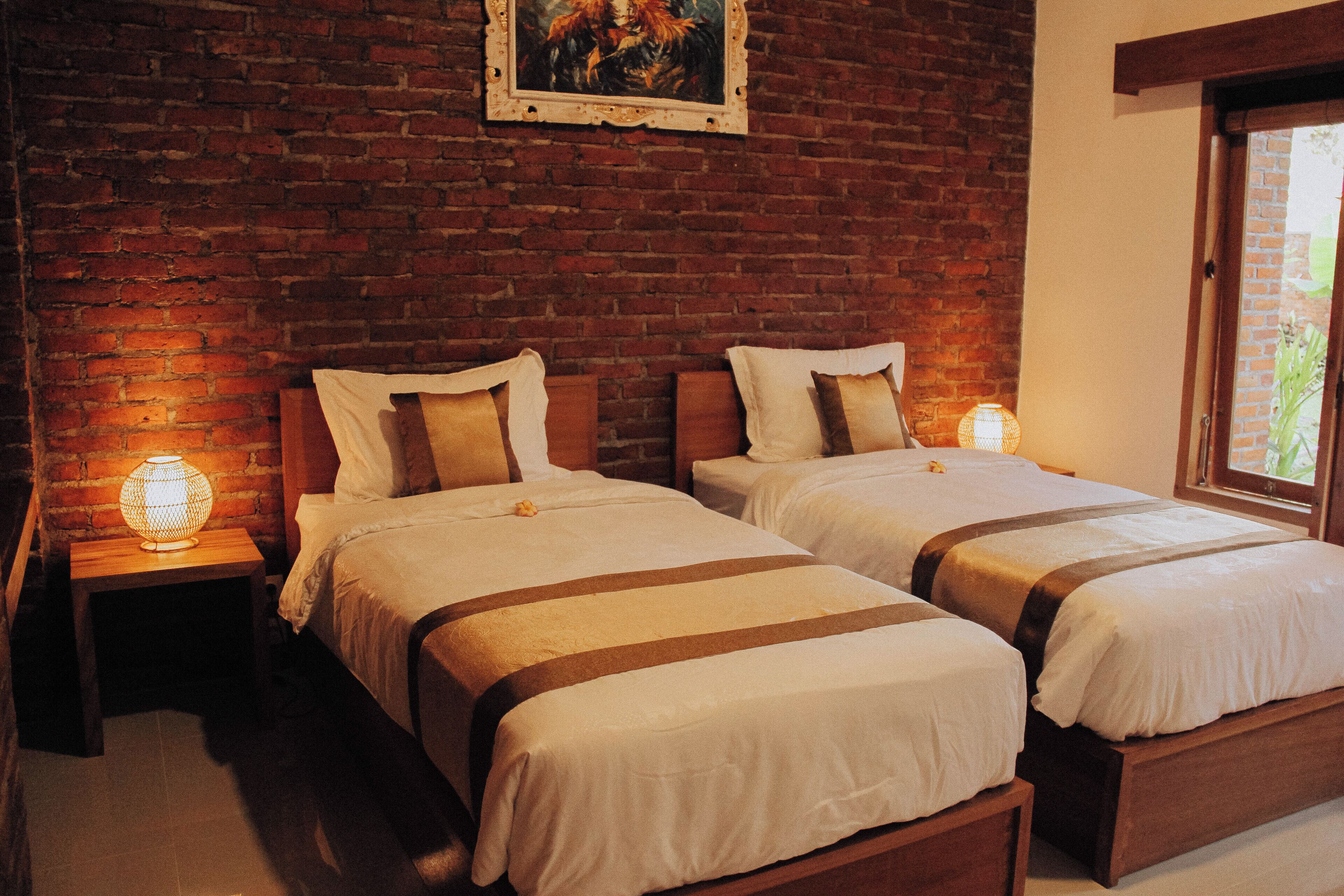 Ein Hotelzimmer mit zwei Betten, Holz-Kopfteilen und einer Ziegelwand.