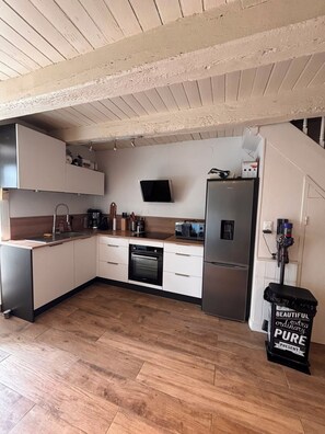 Une cuisine moderne équipée d’un four encastré, d’un réfrigérateur et d’un four à micro-ondes.