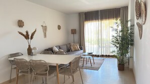 Un salon moderne avec un coin repas, comprenant un canapé, des fauteuils, une table basse et une plante en pot.